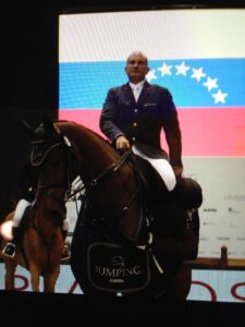 Gustavo Mirabal con la Bandera de Venezuela de fondo mientras suena el himno nacional